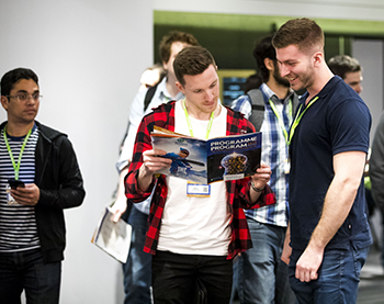 Smiling attendees looking at the conference program.